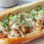 Alabama BBQ Chicken Chopped Sandwich stuffed with crispy chicken, creamy Alabama white BBQ sauce, sliced jalapeños, and chopped green onions on a toasted hoagie roll.