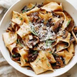 Portobello Mushroom Pappardelle served in a bowl with tender portobello mushrooms, rosemary, and grated Parmesan in a glossy, savory sauce.