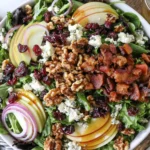 Blue Cheese Apple Walnut Salad topped with crispy bacon, candied walnuts, blue cheese crumbles, sliced apples, dried cranberries, red onion, and maple vinaigrette over fresh mixed greens.