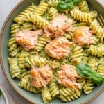 Salmon Pesto Pasta with flaky baked salmon, rotini pasta tossed in creamy basil pesto, and fresh basil garnish for a quick and flavorful dinner.