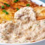 Creamy Crab Rangoon Dip scooped onto a cracker with gooey melted cheese and chunks of real crab