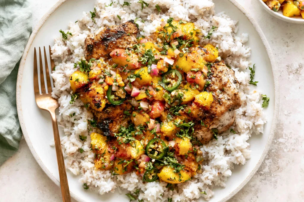 Grilled Jalapeño Peach Chicken served over cilantro lime rice with fresh peach jalapeño salsa, grilled peaches, and sliced jalapeños.