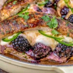 Melty Blackberry Jalapeno Stuffed Chicken baked with melted mozzarella, fresh blackberries, sliced jalapeños, and herbs in a skillet.