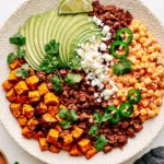 Street Corn Beef Bowl topped with seasoned ground beef, roasted sweet potatoes, creamy Mexican street corn, sliced avocado, cotija cheese, jalapeños, cilantro, and fresh lime.